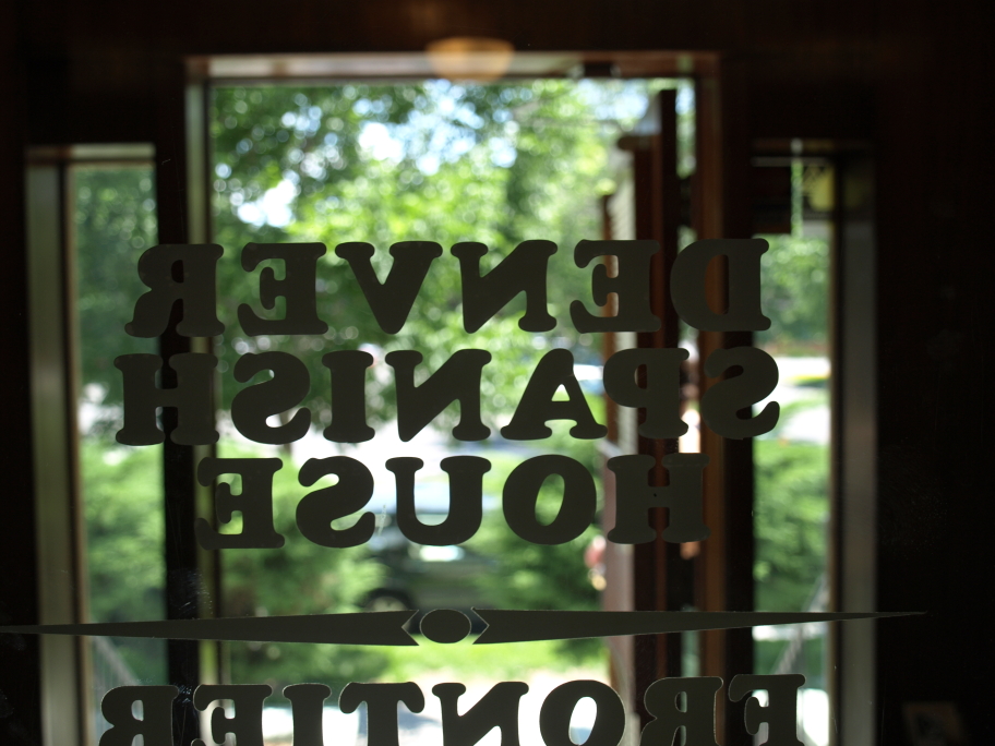 Denver Spanish House glass door sign, looking out at greenery